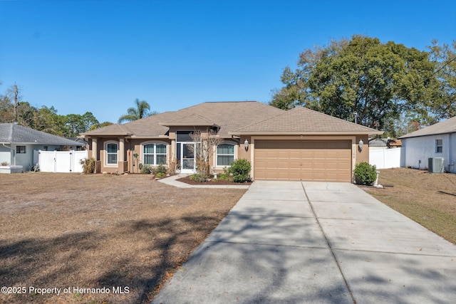 ranch-style home featuring a garage, a front yard, and central air condition unit