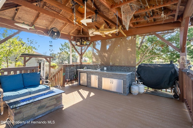 deck featuring area for grilling, a fire pit, and exterior kitchen