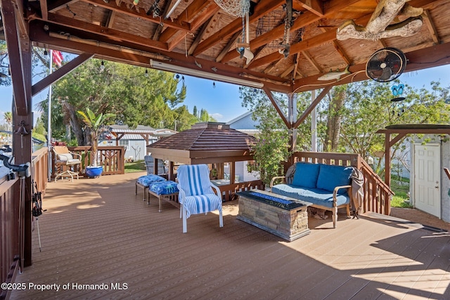 deck with a gazebo, an outdoor living space with a fire pit, and ceiling fan