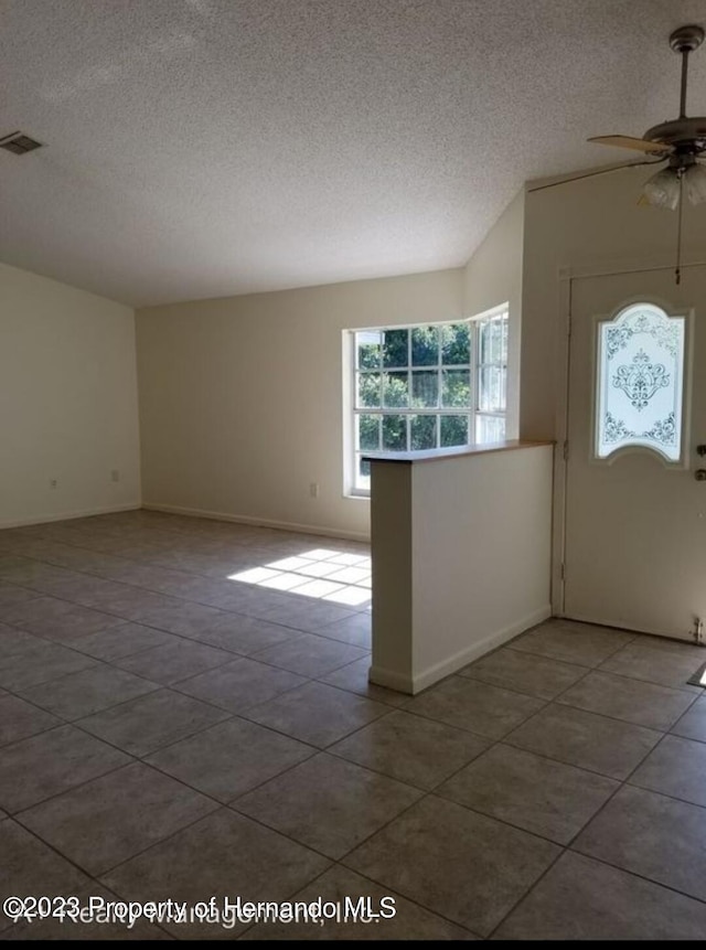 foyer entrance featuring ceiling fan, tile patterned floors, and a textured ceiling