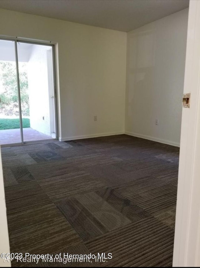 unfurnished room with dark carpet