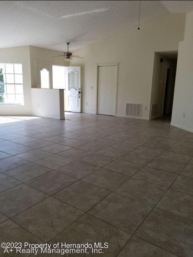 tiled spare room with lofted ceiling, a textured ceiling, and ceiling fan