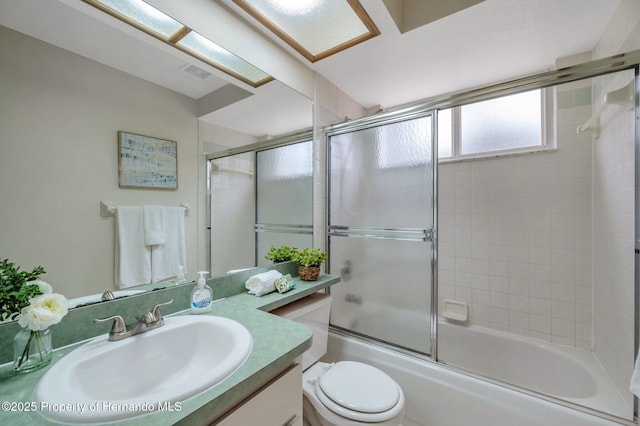 full bathroom with vanity, shower / bath combination with glass door, and toilet