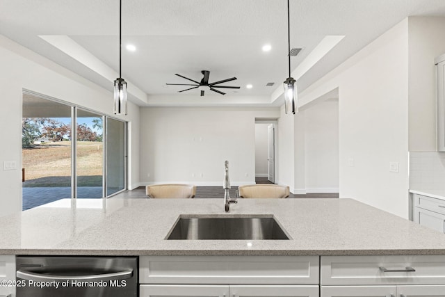 kitchen featuring hanging light fixtures, sink, stainless steel dishwasher, and a raised ceiling