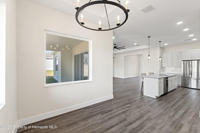 kitchen with dark wood-type flooring, sink, white cabinetry, appliances with stainless steel finishes, and a kitchen island with sink