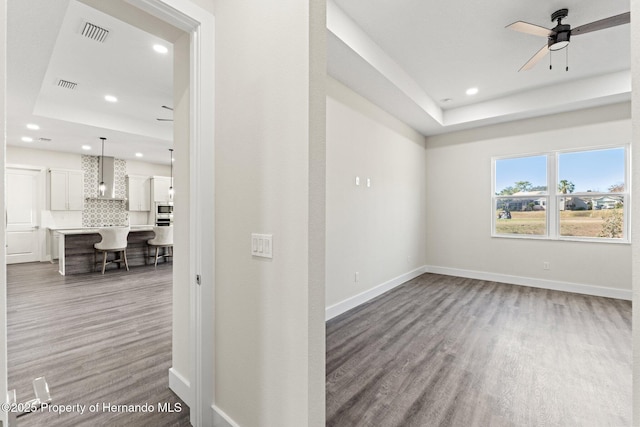 empty room featuring hardwood / wood-style flooring, a raised ceiling, and ceiling fan