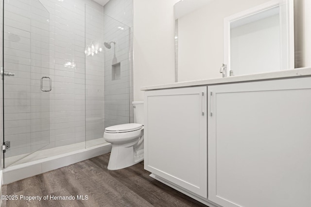 bathroom with hardwood / wood-style flooring, vanity, toilet, and an enclosed shower