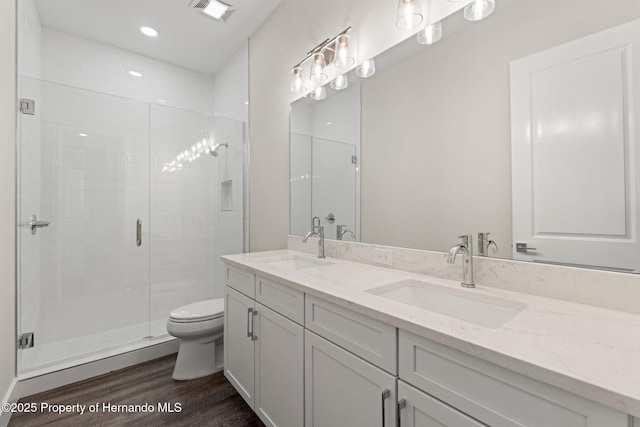 bathroom with hardwood / wood-style flooring, vanity, walk in shower, and toilet