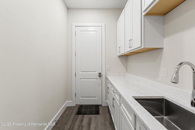 kitchen featuring white cabinetry, sink, dark hardwood / wood-style flooring, and light stone countertops