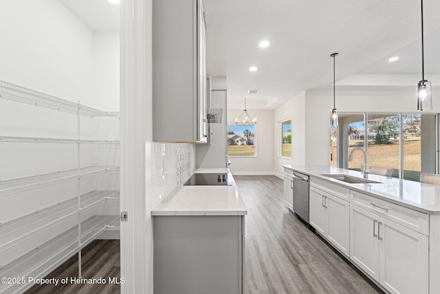 kitchen with light stone counters, sink, decorative light fixtures, and white cabinetry