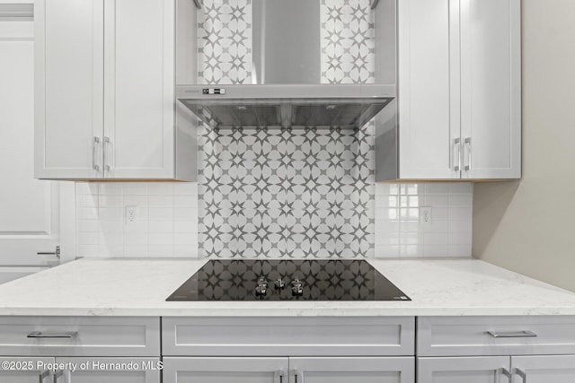 kitchen featuring white cabinetry, black electric stovetop, exhaust hood, and light stone counters