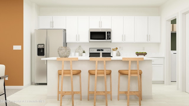 kitchen featuring white cabinetry, stainless steel appliances, an island with sink, and a breakfast bar area