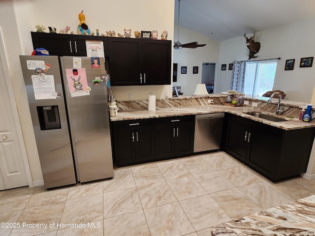 kitchen with appliances with stainless steel finishes, dark cabinetry, a sink, and light stone counters