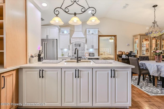 kitchen with high end fridge, sink, white cabinetry, pendant lighting, and light parquet floors