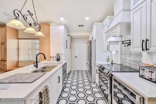 kitchen featuring white cabinetry, appliances with stainless steel finishes, decorative light fixtures, and sink