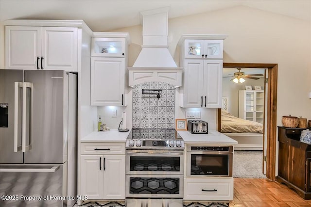 kitchen with light parquet floors, white cabinetry, appliances with stainless steel finishes, and premium range hood