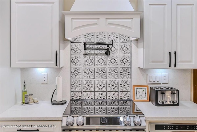 kitchen with white cabinetry, stainless steel range oven, and backsplash