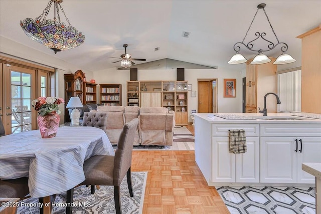 dining space featuring ceiling fan, lofted ceiling, sink, and light parquet floors