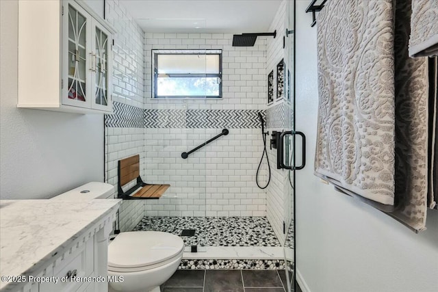 bathroom with tile patterned flooring, vanity, a shower with shower door, and toilet