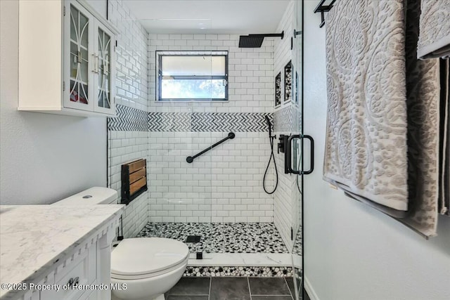 bathroom featuring tile patterned flooring, vanity, a shower with door, and toilet