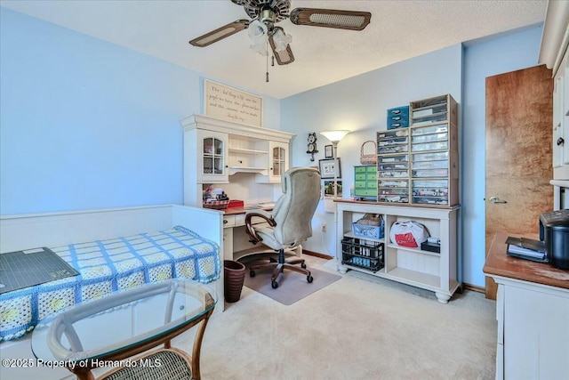 carpeted office with a textured ceiling and ceiling fan