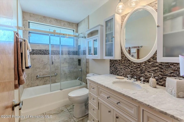 full bathroom featuring bath / shower combo with glass door, toilet, vanity, and decorative backsplash