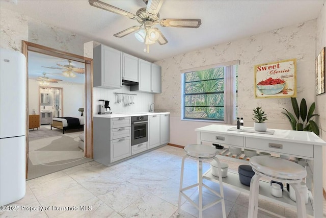 kitchen featuring white refrigerator, stainless steel oven, and ceiling fan