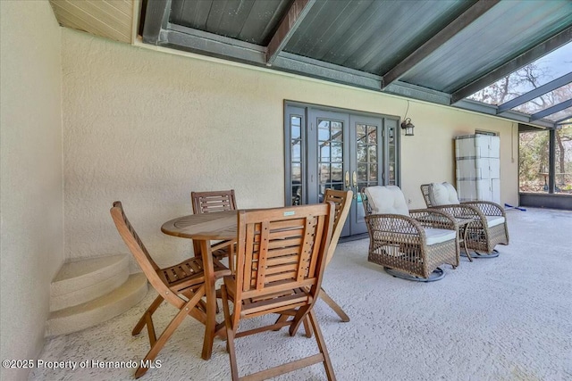 sunroom featuring beamed ceiling and french doors