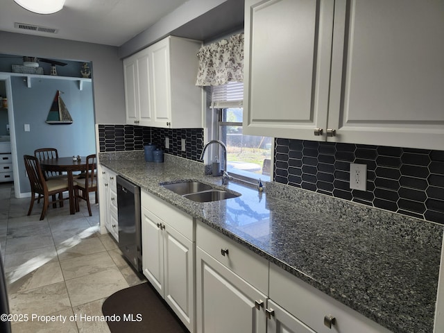 kitchen with sink, black dishwasher, dark stone counters, decorative backsplash, and white cabinets