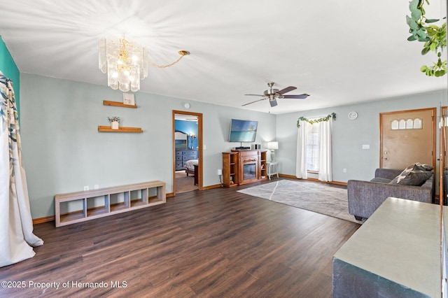 living room with a fireplace, dark hardwood / wood-style floors, and ceiling fan with notable chandelier