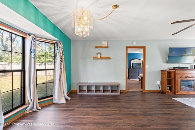 unfurnished dining area with ceiling fan with notable chandelier and dark hardwood / wood-style floors