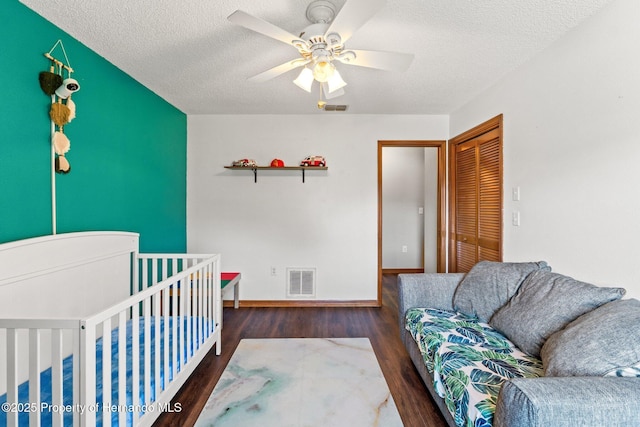 bedroom featuring dark wood-type flooring, ceiling fan, a closet, and a textured ceiling