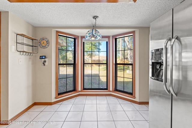 unfurnished dining area with light tile patterned flooring and a textured ceiling