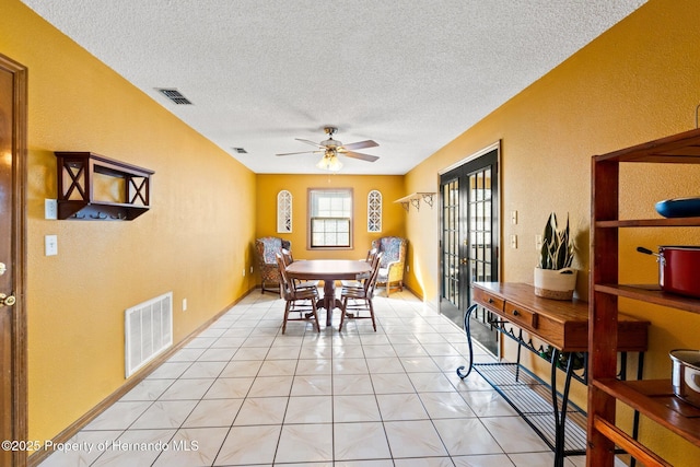 tiled dining area featuring ceiling fan, french doors, and a textured ceiling