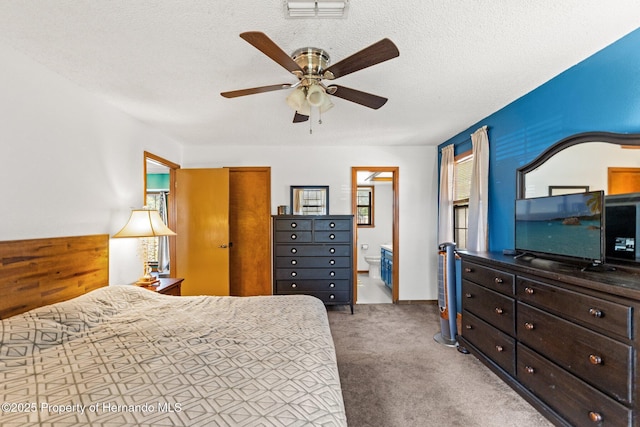 bedroom with ceiling fan, ensuite bath, carpet, and a textured ceiling