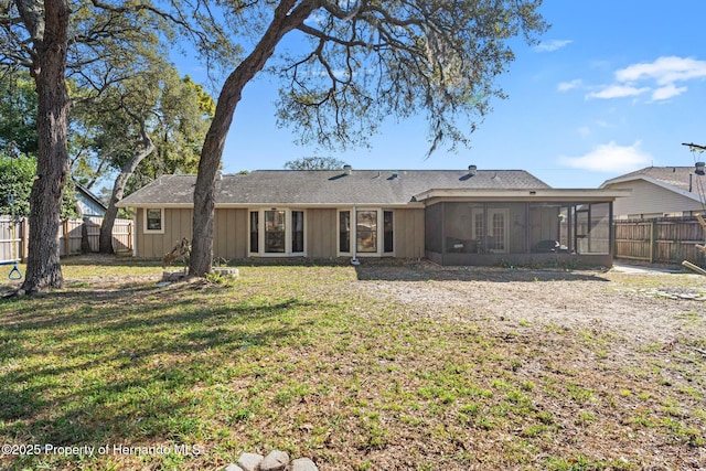 rear view of property featuring a sunroom and a lawn