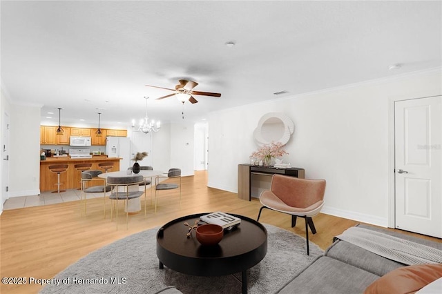 living room featuring ceiling fan with notable chandelier, ornamental molding, and light wood-type flooring