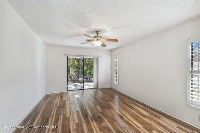 spare room featuring dark wood-type flooring, a textured ceiling, and ceiling fan