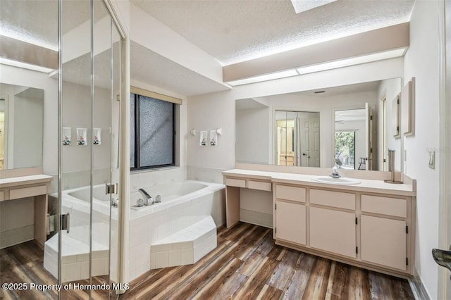 bathroom with hardwood / wood-style flooring, vanity, separate shower and tub, and a textured ceiling