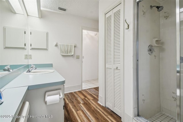 bathroom with vanity, a shower with shower door, hardwood / wood-style floors, and a textured ceiling