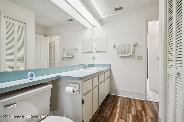 bathroom with vanity, wood-type flooring, a textured ceiling, and toilet