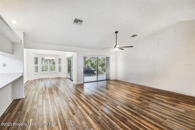 unfurnished living room featuring ceiling fan with notable chandelier, dark hardwood / wood-style flooring, and vaulted ceiling