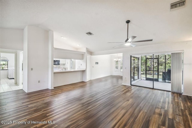 unfurnished living room featuring sink, ceiling fan with notable chandelier, vaulted ceiling, and wood-type flooring