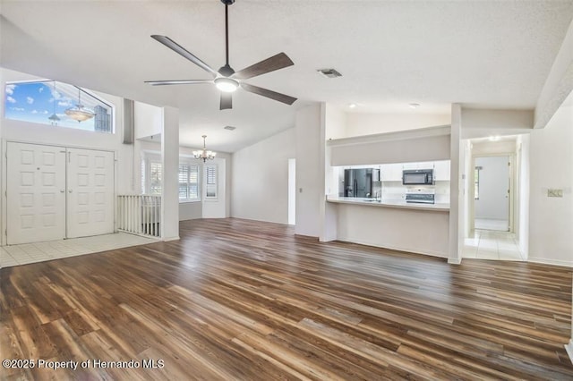 unfurnished living room featuring vaulted ceiling, wood-type flooring, and ceiling fan with notable chandelier