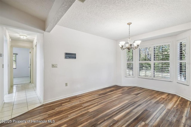 unfurnished dining area featuring hardwood / wood-style flooring, an inviting chandelier, and a textured ceiling