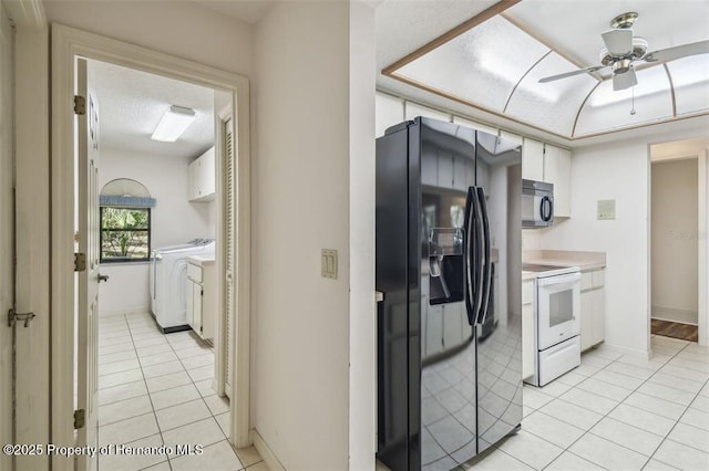 kitchen with white cabinetry, washing machine and dryer, light tile patterned floors, and black appliances