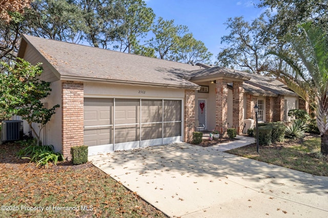 ranch-style home with a garage and central air condition unit