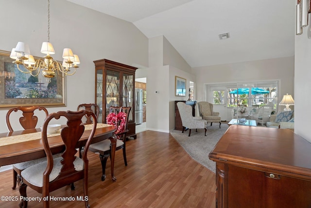 dining room featuring hardwood / wood-style floors, a notable chandelier, and high vaulted ceiling