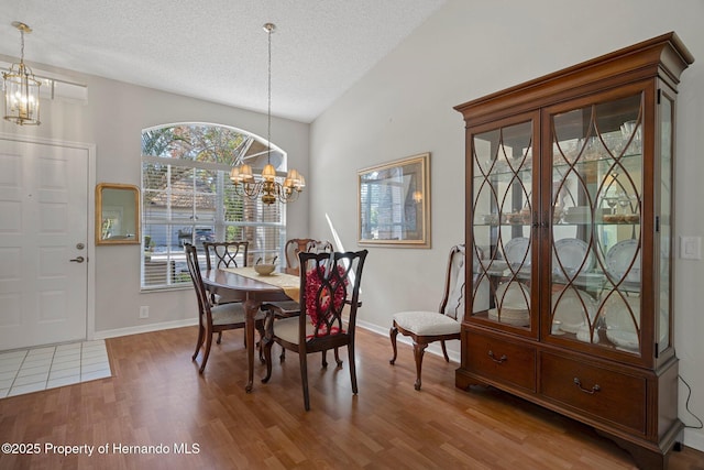 dining space with a textured ceiling, wood-type flooring, and a chandelier