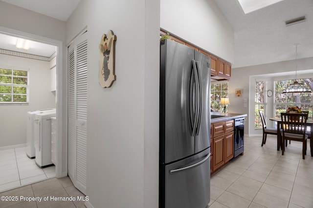 kitchen featuring decorative light fixtures, dishwasher, separate washer and dryer, stainless steel fridge, and light tile patterned floors